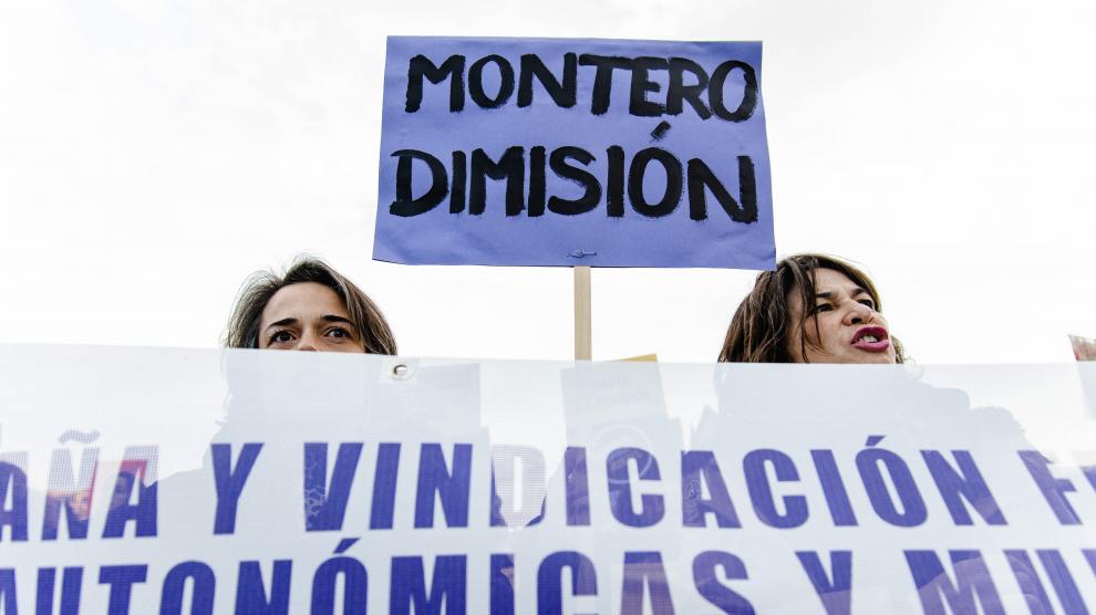 Dos manifestantes en Madrid sostienen una pancarta en la que piden la dimisión de Irene Montero