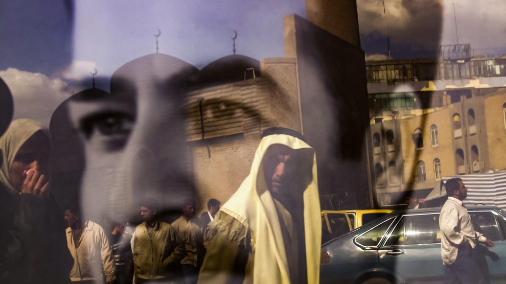 personas que caminan por la calle Rasheed se reflejan en un retrato en blanco y negro del presidente iraquí Saddam Hussein en Bagdad IRAQ PHOTO SET INVASION 20TH ANNIVERSARY