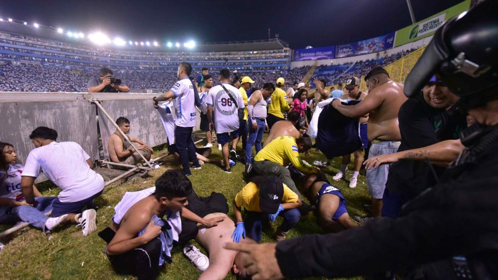 Varios aficionados tratan de auxiliar a algunos de los afectados por la avalancha en el estadio.