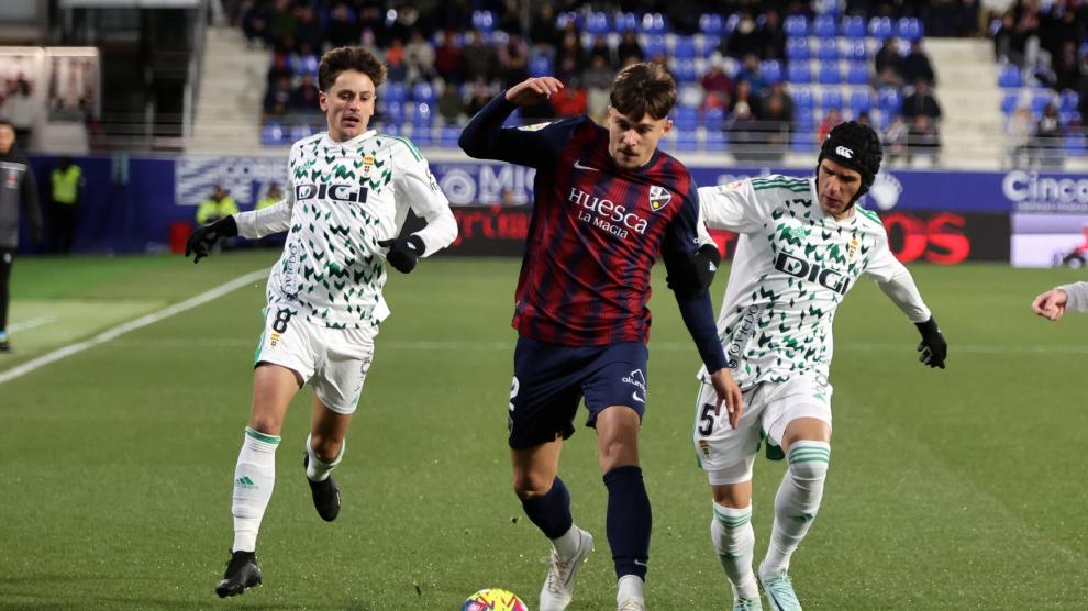 Andrei Ratiu conduce el balón por la banda ante la oposición de dos rivales.