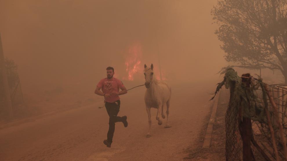 Un granjero corre junto a su caballo para escapar de las llamas en la localidad de Fyli, cerca de Atenas.