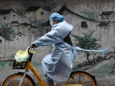 Una mujer en bici se protege del coronavirus en Wuhan, epicentro de la epidemia en China.