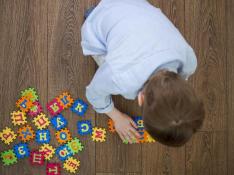 Un niño jugando con unas piezas con letras y símbolos del alfabeto.