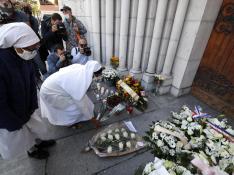 Una religiosa coloca un ramo de flores en la entrada de la iglesia de Notre Dame, en Niza, donde ocurrió el atentado.