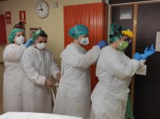 Las auxiliares María José, Silvia y Lara y la enfermera Raquel, colocándose los equipos de protección para la jornada.