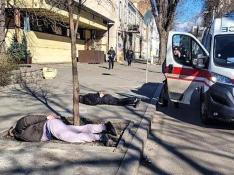 Dos personas esposadas y tendidas en el suelo junto a una ambulancia en una de las ciudades sitiadas