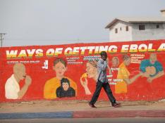 Un ciudadano de Liberia pasea por delante de un mural divulgativo pintado para concienciar sobre la epidemia de ébola.
