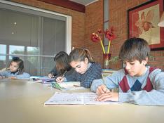 Niños de diferentes edades haciendo deberes en su casa.
