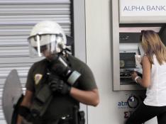 Una mujer saca dinero en un cajero de Atenas