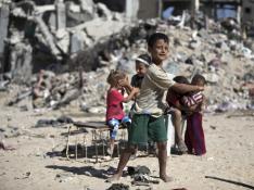 Niños palestinos caminan entre escombros