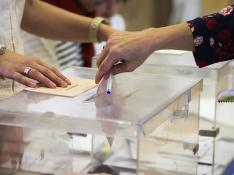 Una mujer deposita su voto en una urna de un colegio de Valladolid, en la jornada de elecciones generales que vive hoy el país.