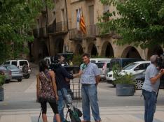 El alcalde Joaquim Paladella, en el centro de la foto, atiende a una televisión en la plaza de Batea, delante del Ayuntamiento.