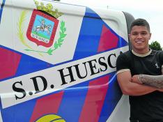 El jovencísimo delantero Juan Camilo 'Cucho' Hernández posa junto a uno de los vehículos que utiliza el Huesca diariamente para el traslado de material.