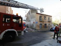 Bomberos de Zaragoza trabajan para sofocar el incendio en una casa con okupas junto al río Huerva
