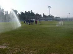 El grupo de jugadores del Real Zaragoza, al inicio del entrenamiento de este martes entre los aspersores de la Ciudad Deportiva.
