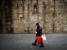 Una persona protegida contra el virus pasa por delante de la imagen de San Fermín en el primer tramo del encierro