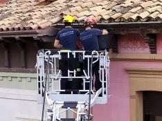 Los bomberos retiran material desprendido en el alero de un edificio del Coso Bajo