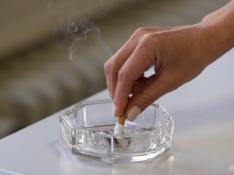 Una fumadora apagando un cigarrillo en un cenicero