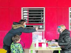 Una mujer vota en la secretaría del colegio Marie Curie de Zaragoza instalada en el porche de infantil.
