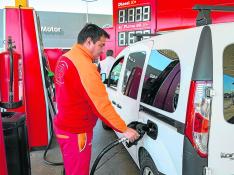 Un trabajador de una gasolinera carga combustible en un vehículo