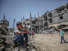 Un niño sentado sobre las ruinas de un edificio derribado en Gaza