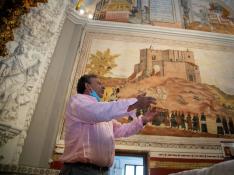 El alcalde de Bijuesca explica cómo es la romería de la Saca de la Virgen ante una pìntura de la ermita que la reproduce