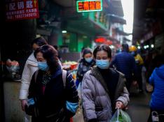 Gente con mascarillas por la calle del mercado de Wuhan donde arrancó la pandemia
