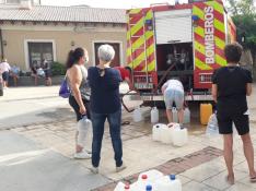 Vecinos de Laguarres hacen cola para llenar de agua sus garrafas en el camión de bomberos.