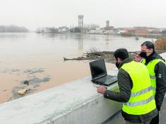 Dos técnicos de la CHE siguen la crecida en Cabañas y analizan en el ordenador modelizaciones del comportamiento del río.