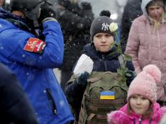 Refugiados ucranianos reciben flores a su llegada bajo la nieve a la frontera con Rumanía.