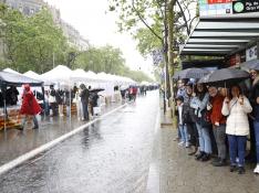 Ciudadanos se resguardan del chaparrón tras desafíar a la lluvia y visitar las casetas de venta de libros en el Paseo de Gràcia