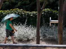 Un mujer pasea por Madrid Río protegida por un paraguas, el pasado jueves.