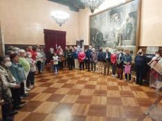 El alcalde se dirige a un grupo de visitantes en el salón del Justicia, con el célebre cuadro de La Campana de Huesca.