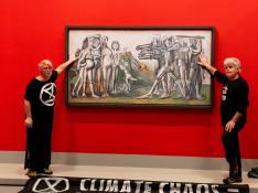 Los dos activistas, con las manos pegadas al cuadro de Picasso.