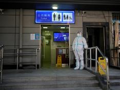 A worker in protective suit keeps a watch outside a public toilet in Shanghai