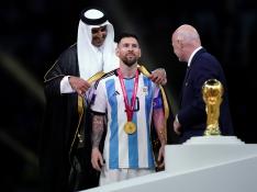 El emir de Qatar, el jeque Tamim bin Hamad Al Thani viste a Lionel Messi de Argentina con bisht árabe tradicional antes de entregarle la copa de campeón del mundo