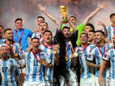 El argentino Lionel Messi sostiene el trofeo de la Copa del Mundo mientras el equipo celebra después del último partido de fútbol de la Copa Mundial de la FIFA Qatar 2022 entre Argentina y Francia en el Lusail Stadium.