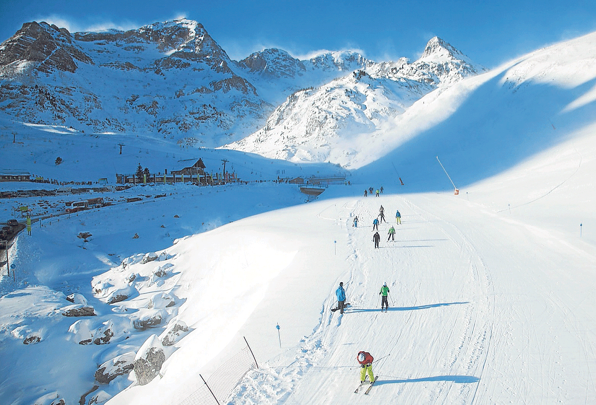 Esquiadores en la estación de Formigal, en cuyas cumbres se ve la nieve que levanta el viento