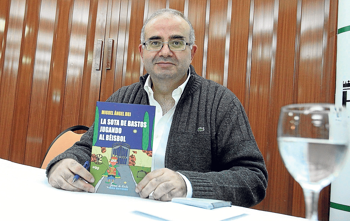 Miguel Ángel Buj posa con un ejemplar de su libro 'La sota de bastos jugando al béisbol'