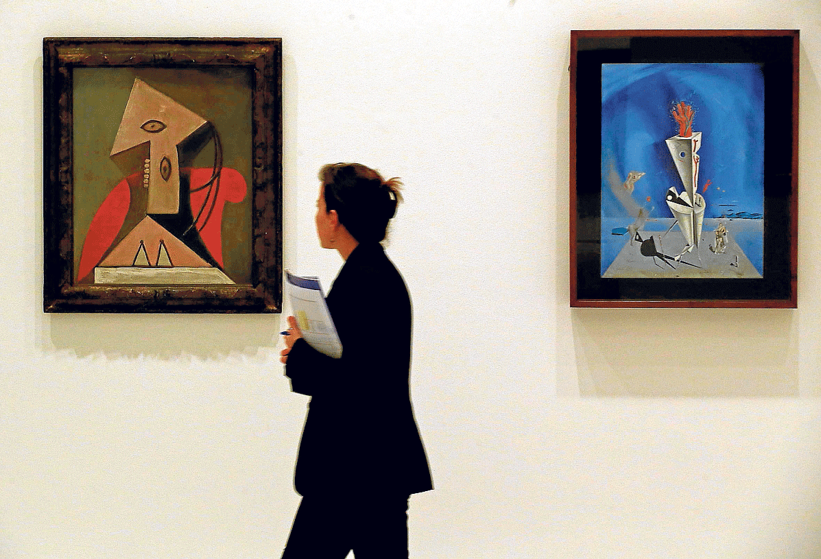 Una visitante del museo, entre obras de Picasso, a la izquierda, y Dalí ('Aparato y mano')