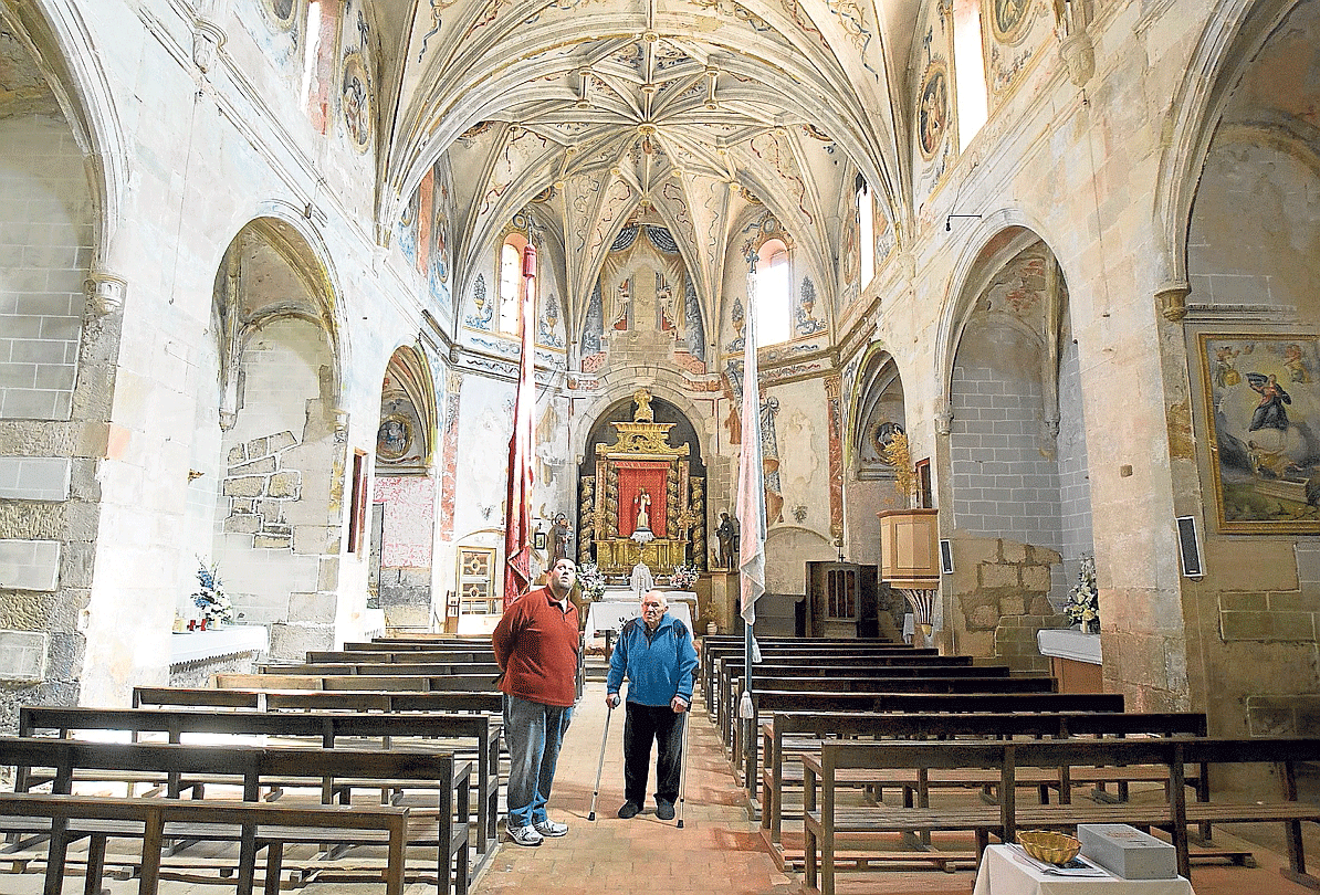 Dos vecinos de Miravete contemplan la iglesia, un templo gótico del siglo XVI.