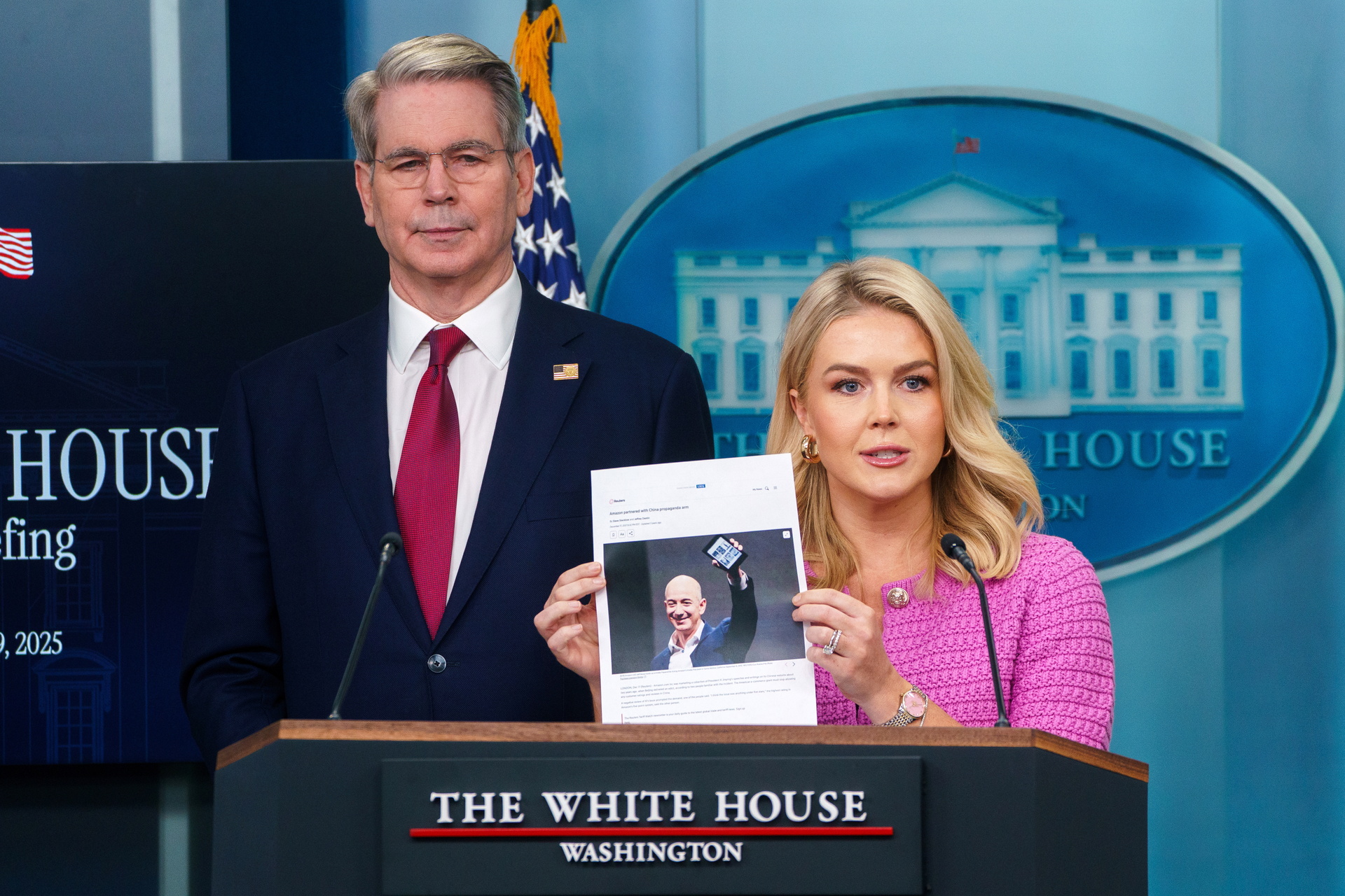 La secretaria de prensa de la Casa Blanca, Karoline Leavitt, sostiene una fotografía del fundador de Amazon, Jeff Bezos, con el secretario del Tesoro de Estados Unidos, Scott Bessent (izquierda), durante una rueda de prensa en la Casa Blanca este martes.